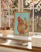 Framed art print of a chicken on a windowsill with autumn decor.