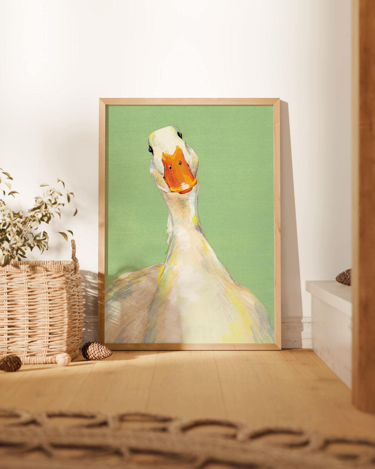 Framed artwork of a goose on a green background in a room with a basket and plant.