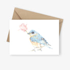 Greeting card featuring bluebird holding a pink magnolia flower.