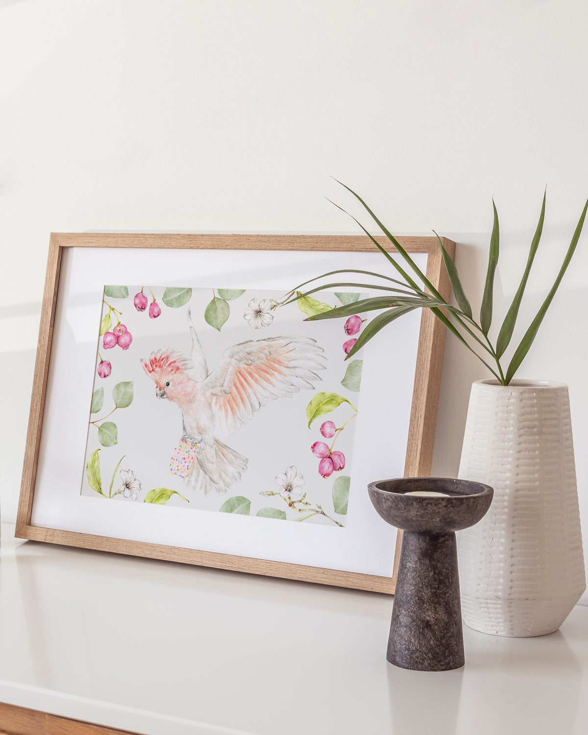 Nursery artwork of a pink cockatoo holding a biscuit